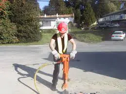 A man in red hard hat holding an orange hose.