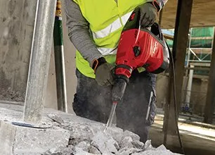 15-1920w A man in yellow vest using a red and black electric hammer.