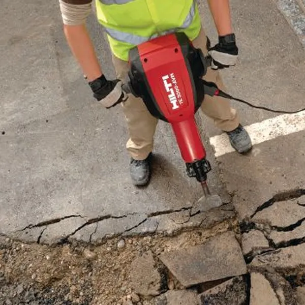 A person holding a red hammer on the ground.