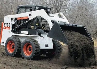 A large white and black tractor is pulling dirt