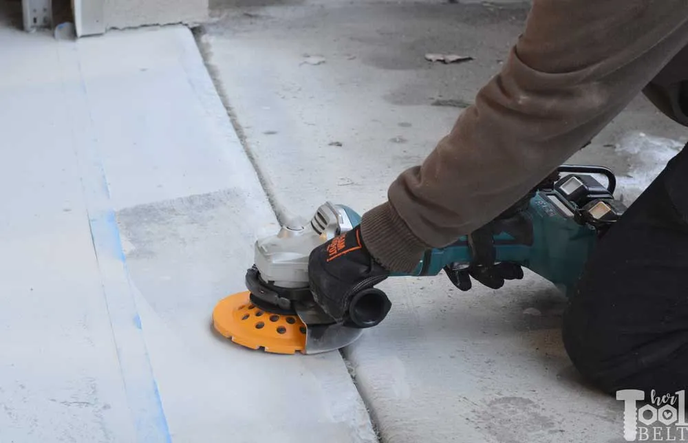 A person using an angle grinder to cut the floor.