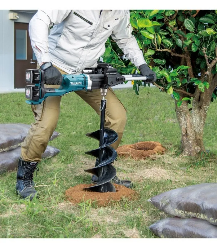 A man with a drill in the grass.