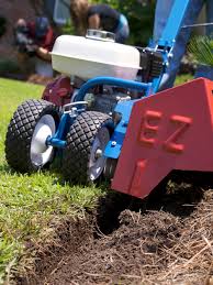 A blue and white tractor with a red plow in the grass.