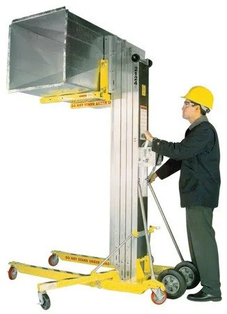 A man in yellow hard hat holding onto a lift.
