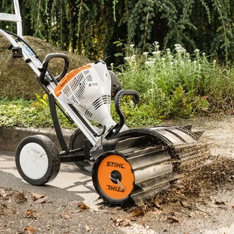 A small machine is sweeping leaves on the ground.