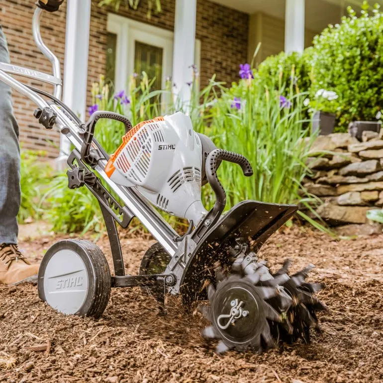 A person is using a garden tool to work in the yard.