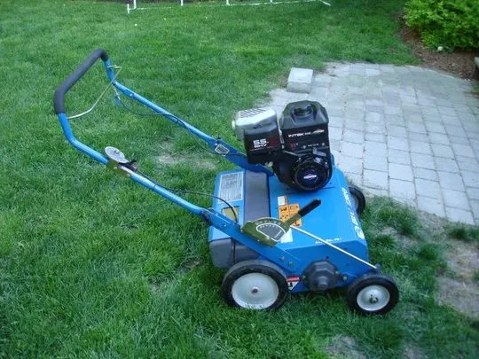 A blue lawn mower sitting in the grass.