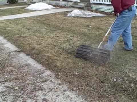 A person raking grass with an attachment.