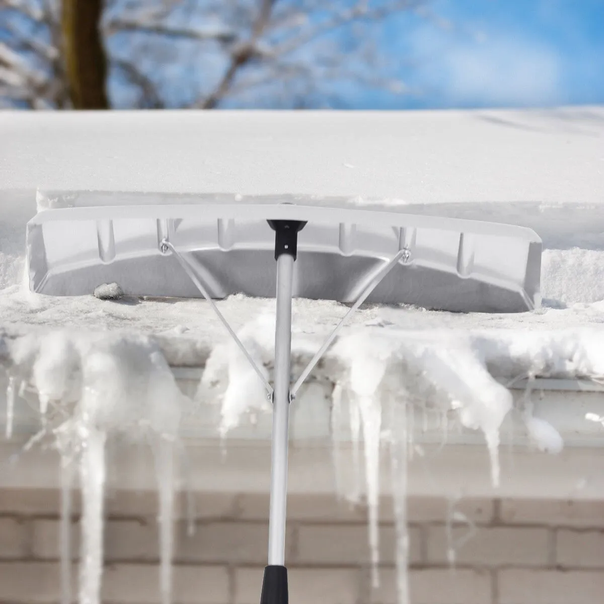 A snow shovel is covered with ice on the roof of a house.