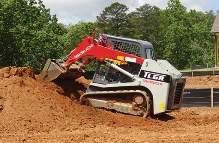 A red and white tractor is digging in the dirt