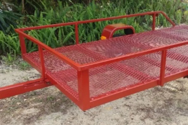 A red trailer with a metal frame and a handle.